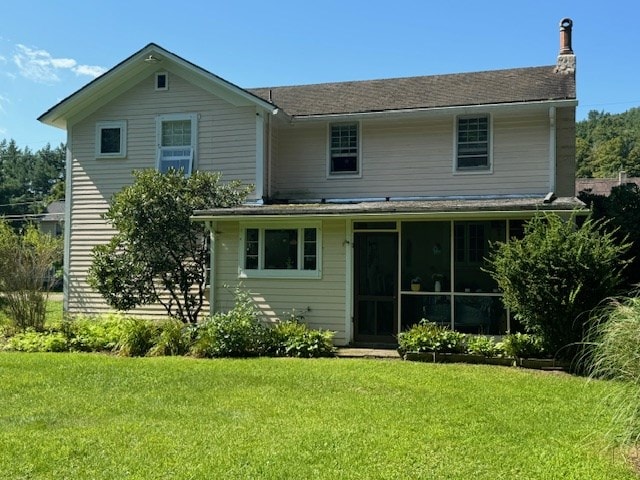 back of property with a sunroom and a lawn