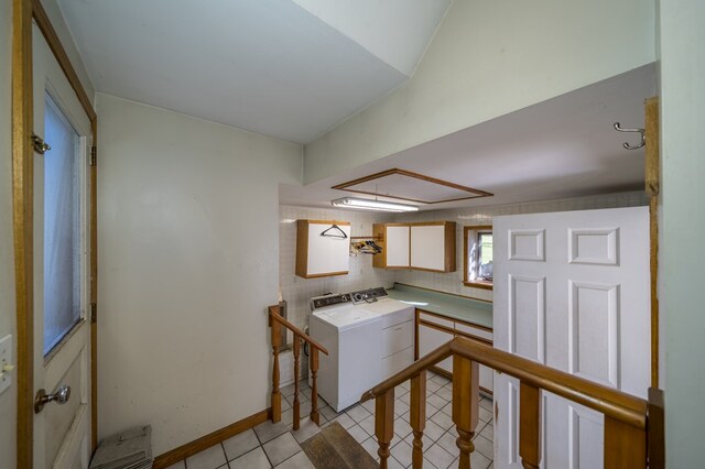 kitchen featuring white cabinets, light tile patterned flooring, and washing machine and dryer