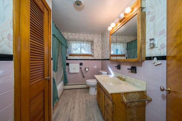 bathroom featuring a baseboard heating unit, toilet, vanity, tile walls, and hardwood / wood-style flooring