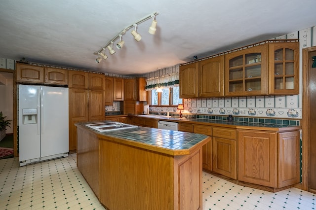 kitchen featuring tile countertops, a center island, white appliances, and sink