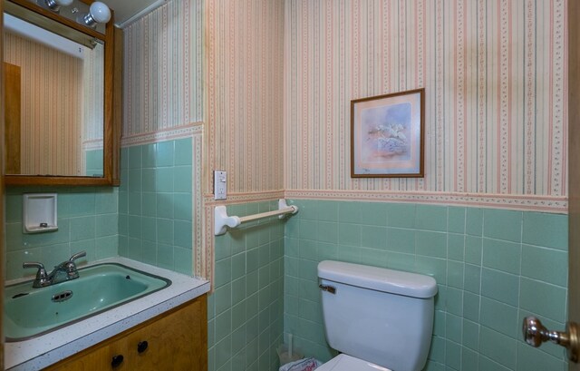 bathroom with vanity, toilet, and tile walls