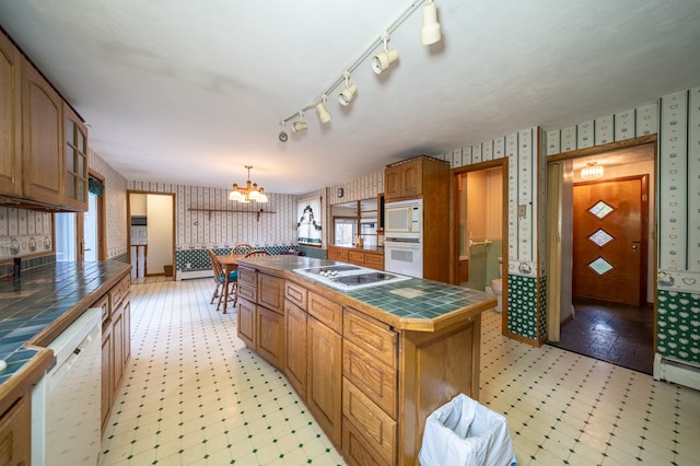 kitchen featuring a center island, hanging light fixtures, an inviting chandelier, tile countertops, and white appliances