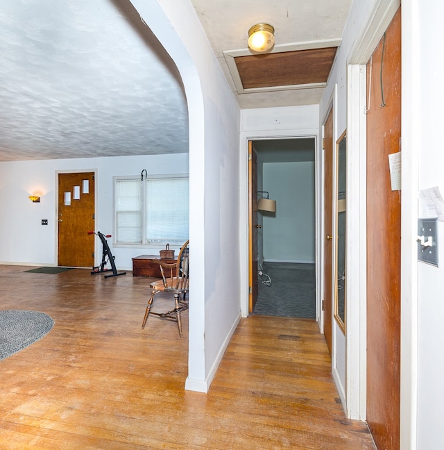 hallway with a textured ceiling and light hardwood / wood-style floors