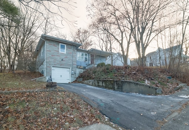view of front of home featuring driveway, a garage, and stone siding