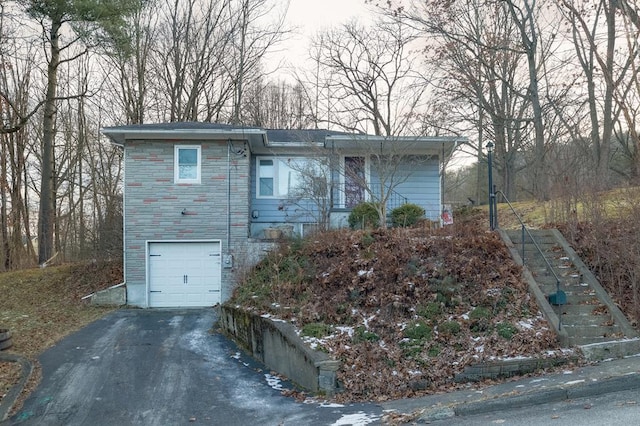 view of front of property with asphalt driveway, a garage, and stone siding