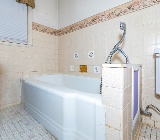 bathroom featuring tile patterned floors, a bathing tub, and tile walls