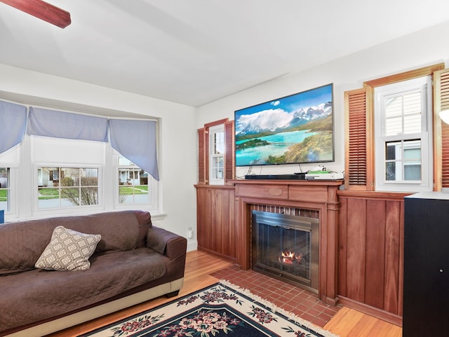 living area with a fireplace with flush hearth, baseboards, and light wood-style floors