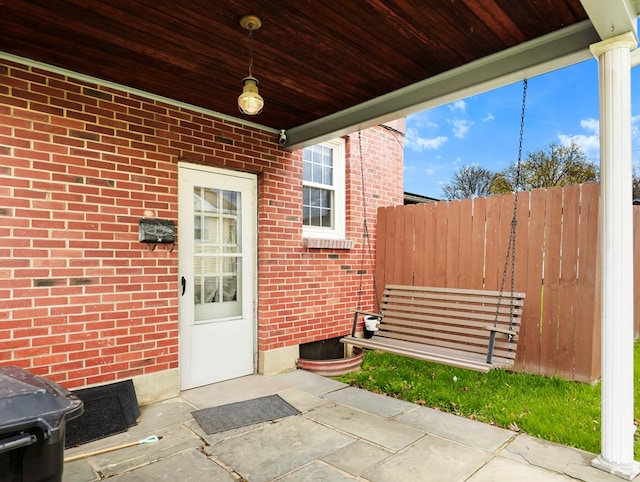 property entrance featuring brick siding and fence