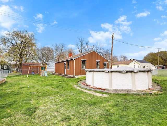 view of yard with a playground, fence, and a covered pool