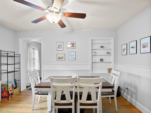 dining room with built in features, a ceiling fan, and wood finished floors