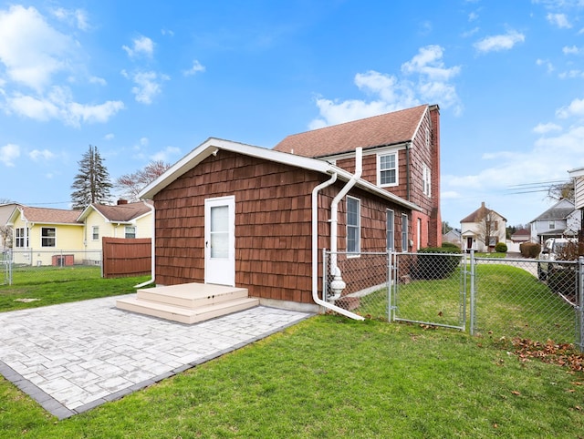 back of property with fence, a gate, a patio, and a lawn
