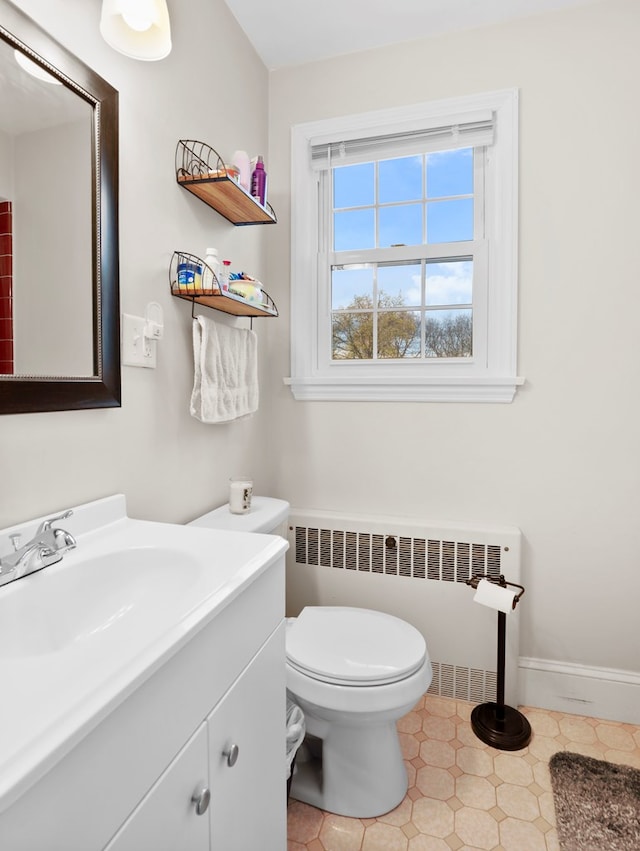 bathroom with vanity, baseboards, radiator heating unit, and toilet