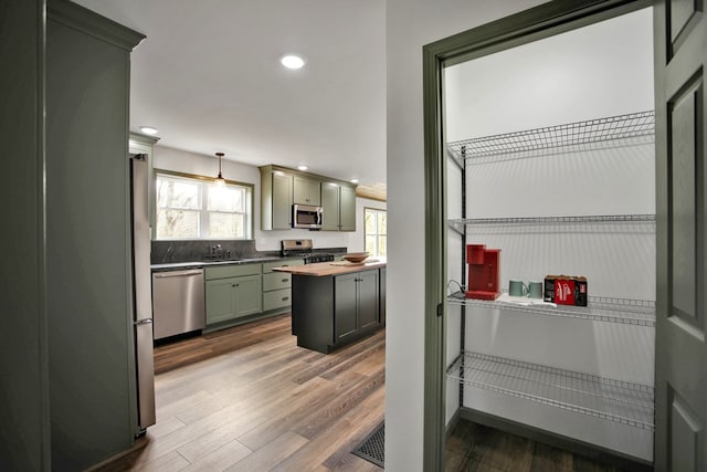 kitchen with pendant lighting, appliances with stainless steel finishes, dark hardwood / wood-style floors, and sink