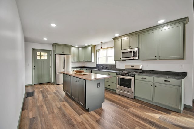 kitchen featuring pendant lighting, appliances with stainless steel finishes, dark hardwood / wood-style flooring, and a center island