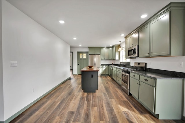 kitchen with dark wood-type flooring, green cabinetry, hanging light fixtures, a kitchen island, and stainless steel appliances