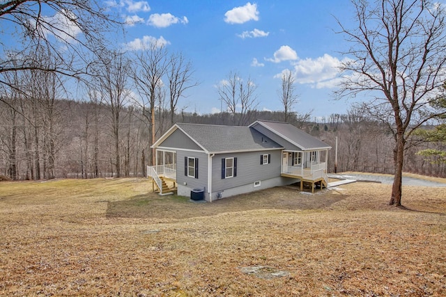 view of side of home with cooling unit, a lawn, and covered porch