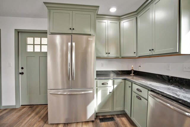 kitchen with dark stone countertops, stainless steel appliances, and dark hardwood / wood-style floors