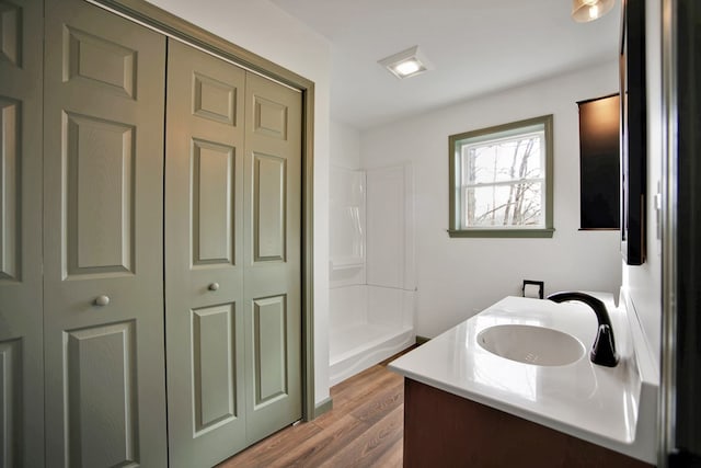 bathroom featuring wood-type flooring, a shower, and vanity