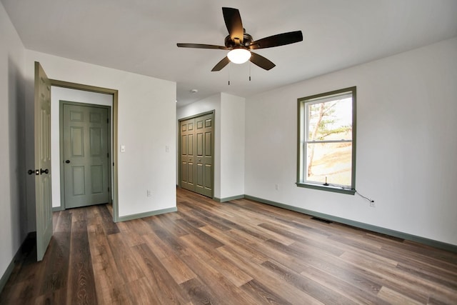 unfurnished bedroom with dark wood-type flooring, ceiling fan, and a closet