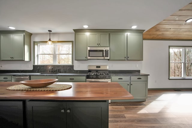 kitchen with appliances with stainless steel finishes, sink, wooden counters, and green cabinetry