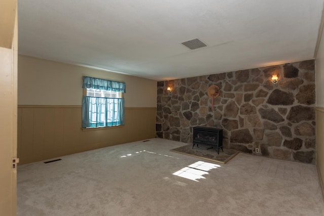 unfurnished living room with light colored carpet and a wood stove