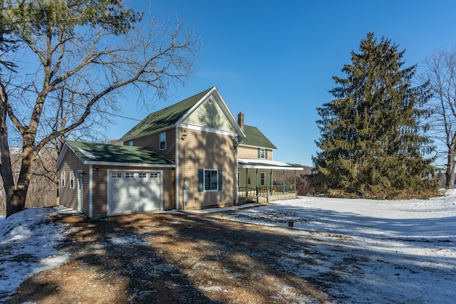 view of snowy exterior with a garage and covered porch