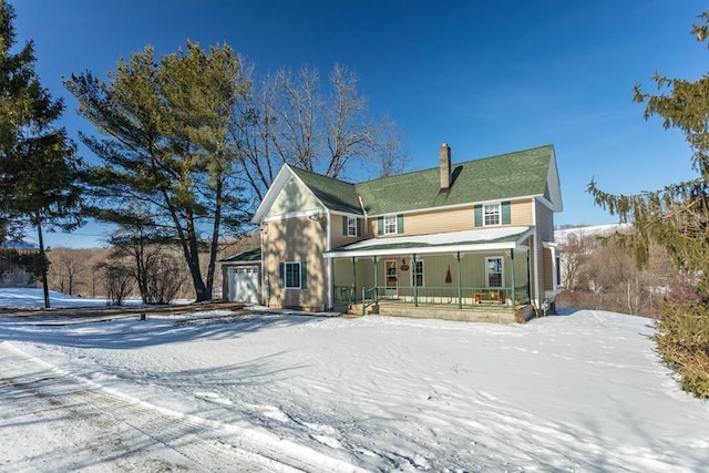 snow covered house featuring a garage and covered porch