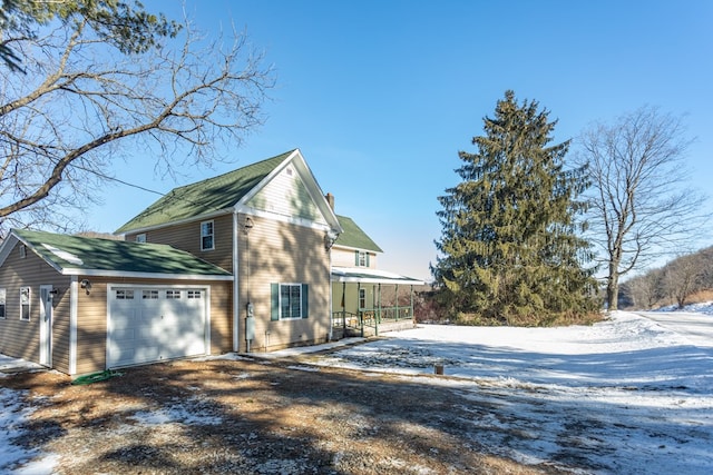 view of snow covered exterior with a garage and covered porch