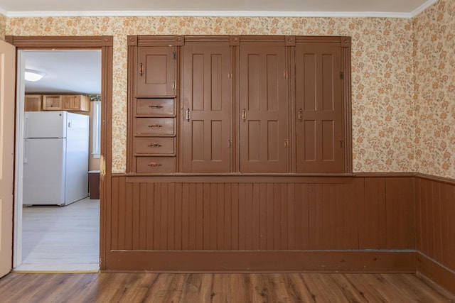 room details with white refrigerator, crown molding, and wood-type flooring