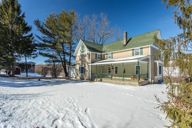 snow covered rear of property with covered porch