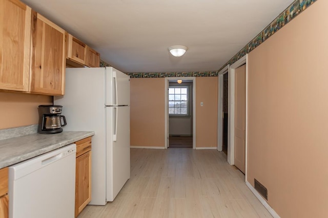 kitchen with white appliances, light hardwood / wood-style floors, and light brown cabinets