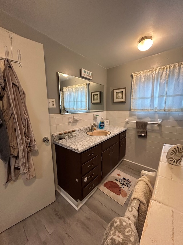 bathroom featuring a wainscoted wall, tile walls, vanity, and wood finished floors