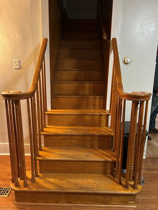 stairway featuring wood finished floors and visible vents