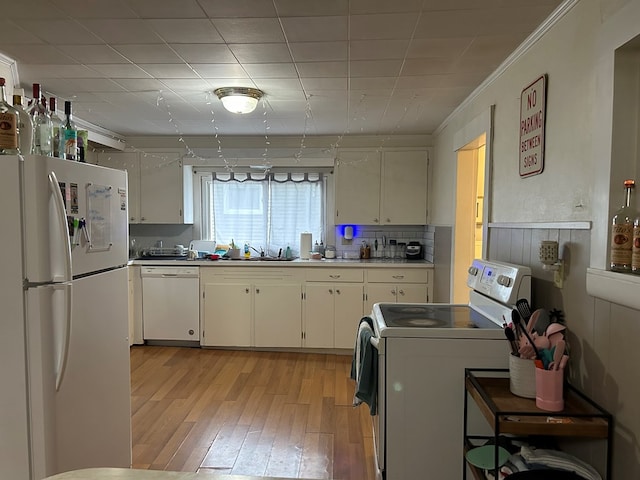 kitchen with crown molding, light wood-style floors, white cabinets, white appliances, and a sink