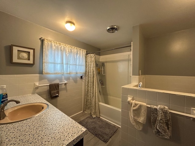 full bath with shower / bathtub combination with curtain, visible vents, tile walls, wainscoting, and vanity