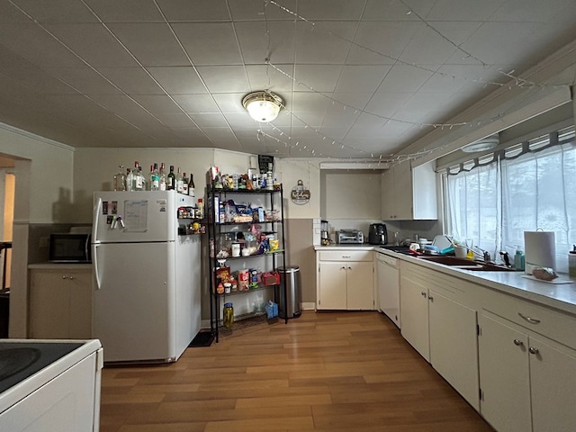 kitchen featuring light wood finished floors, white appliances, light countertops, and a sink