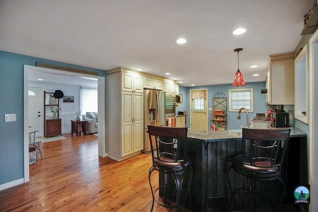 kitchen featuring a kitchen breakfast bar, cream cabinets, and hanging light fixtures