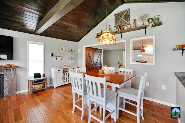 dining room featuring a fireplace, lofted ceiling with beams, light hardwood / wood-style floors, and wood ceiling