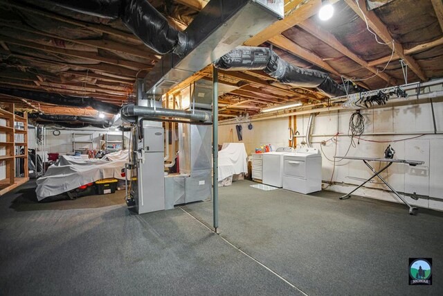 basement featuring heating unit and washing machine and clothes dryer