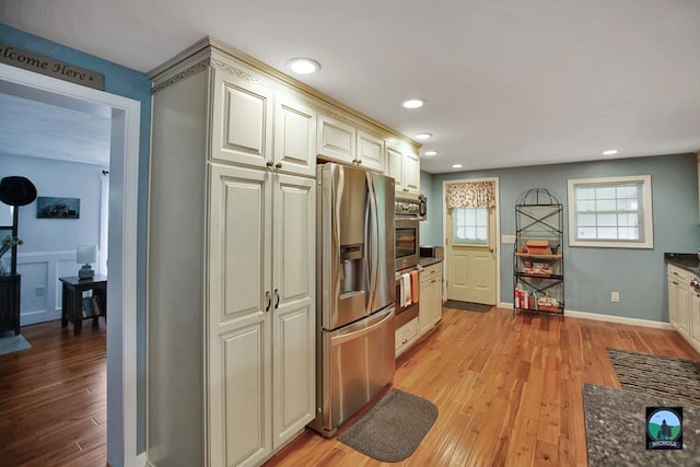 kitchen with cream cabinetry, appliances with stainless steel finishes, and light hardwood / wood-style flooring