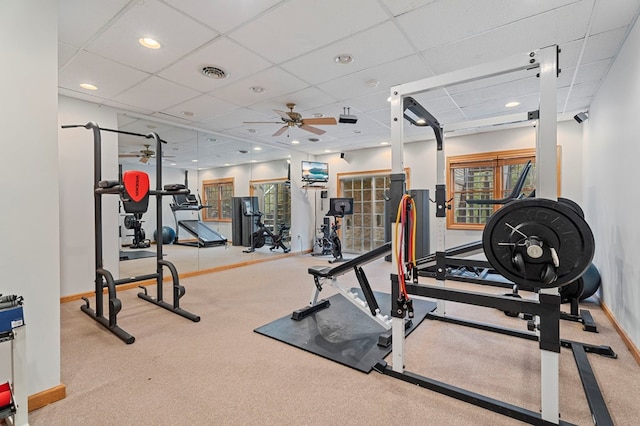 exercise room with ceiling fan, a drop ceiling, and light colored carpet