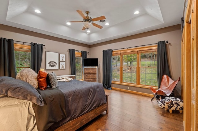 bedroom featuring hardwood / wood-style floors, a tray ceiling, and ceiling fan