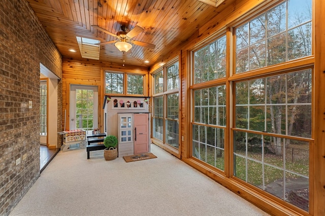 unfurnished sunroom with a skylight, ceiling fan, and wood ceiling