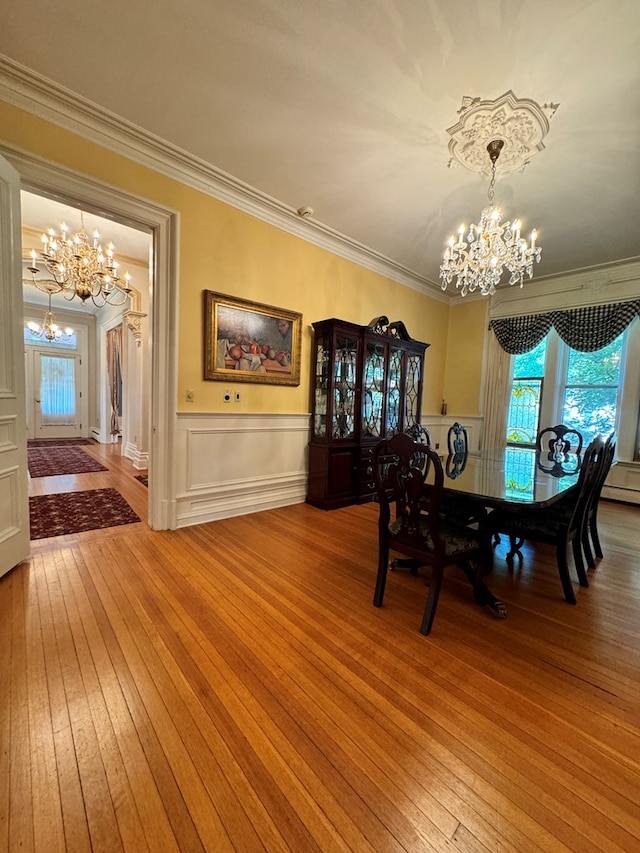 unfurnished dining area with hardwood / wood-style flooring, ornamental molding, and an inviting chandelier