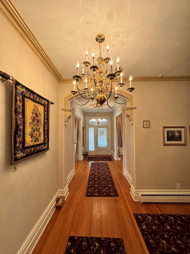 hallway featuring baseboard heating, an inviting chandelier, wood-type flooring, and ornamental molding