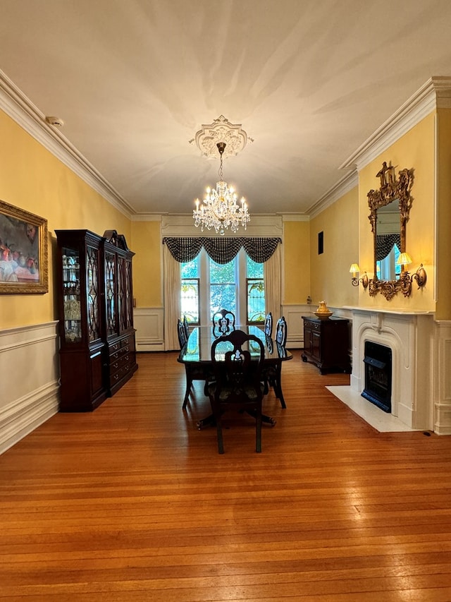 dining area with a notable chandelier, wood-type flooring, and ornamental molding