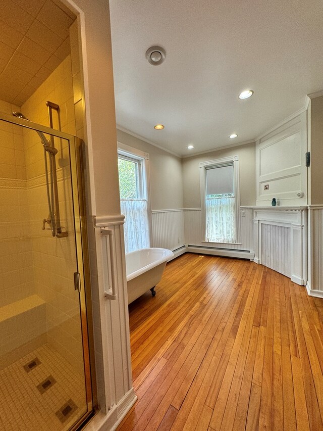 interior space featuring ornamental molding, plus walk in shower, a baseboard radiator, and wood-type flooring