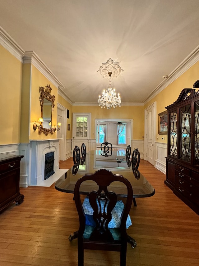 dining area featuring light hardwood / wood-style floors, ornamental molding, and an inviting chandelier