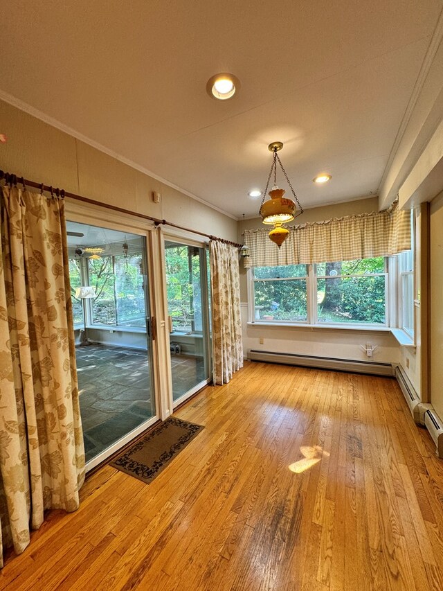 unfurnished dining area with wood-type flooring, ornamental molding, and baseboard heating