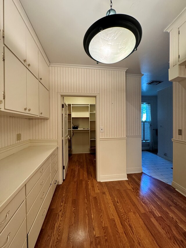 kitchen with white cabinets, dark hardwood / wood-style floors, ornamental molding, and hanging light fixtures